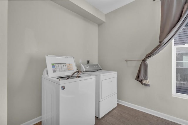 clothes washing area featuring laundry area, dark wood-style flooring, baseboards, and separate washer and dryer