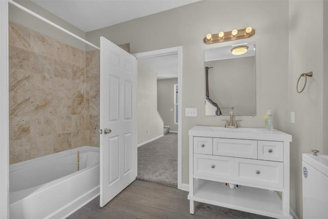 full bathroom with baseboards, toilet, vanity, wood finished floors, and washtub / shower combination