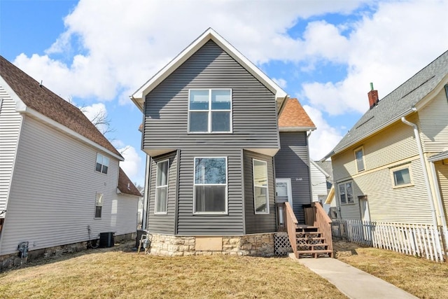 rear view of property with central air condition unit, a yard, and fence