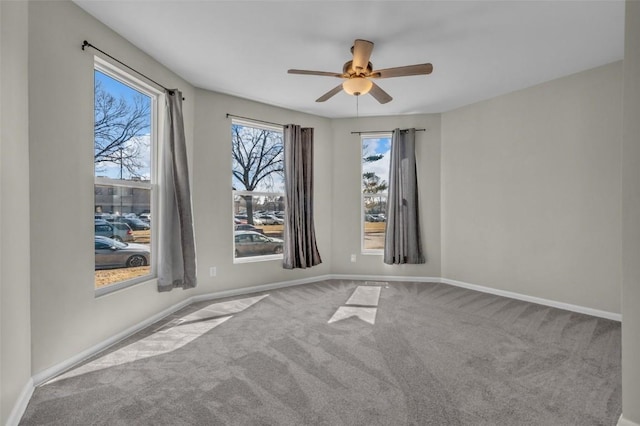 carpeted empty room featuring baseboards and ceiling fan