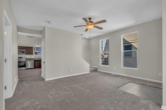 carpeted spare room featuring baseboards and ceiling fan