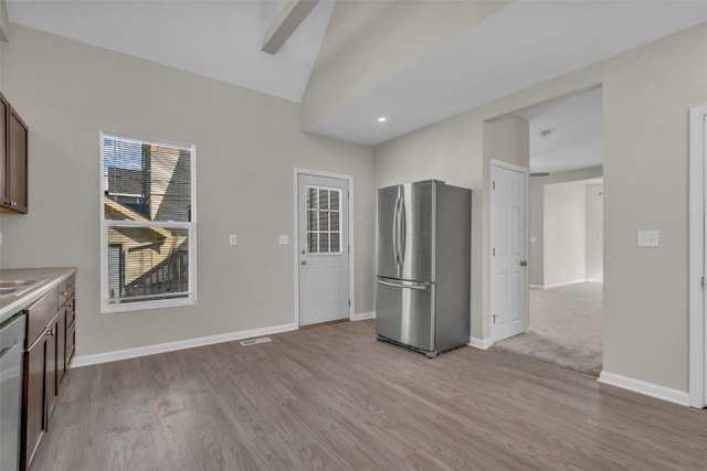 kitchen with stainless steel appliances, lofted ceiling, baseboards, and light wood finished floors