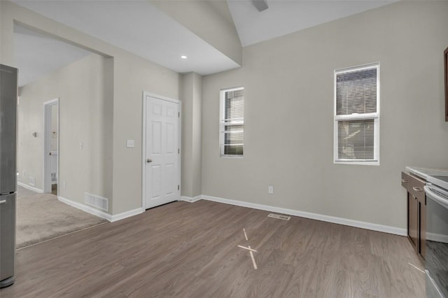 spare room featuring visible vents, lofted ceiling, baseboards, and wood finished floors