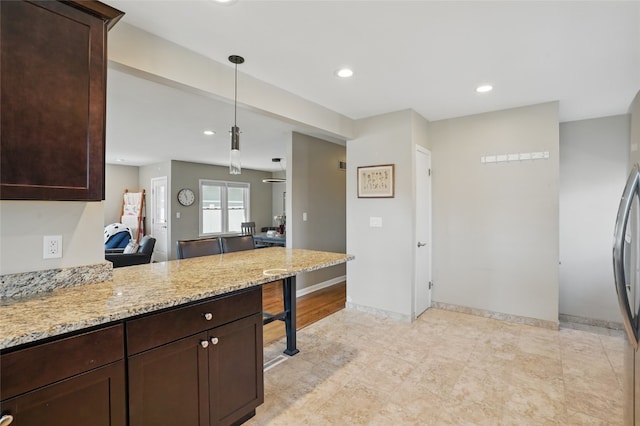 kitchen featuring light stone counters, dark brown cabinets, and a peninsula