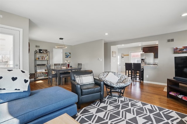 living area with recessed lighting, visible vents, baseboards, and wood finished floors