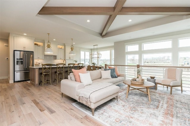 living room featuring light wood-type flooring, beamed ceiling, baseboards, and recessed lighting