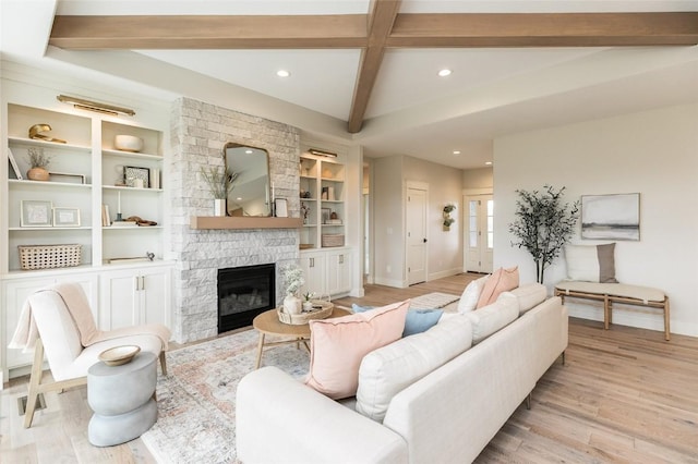 living area featuring beamed ceiling, recessed lighting, light wood-style floors, a stone fireplace, and baseboards