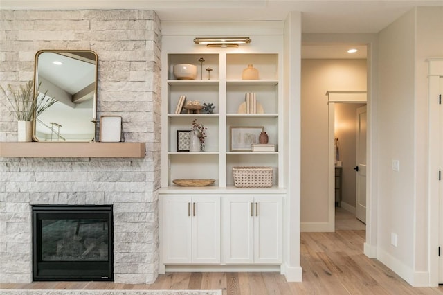 interior details featuring built in features, baseboards, wood finished floors, and a fireplace