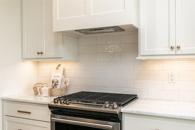 kitchen featuring light stone countertops, custom exhaust hood, decorative backsplash, white cabinets, and stainless steel gas stove