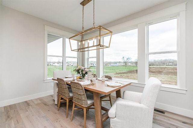 dining space featuring visible vents, baseboards, light wood-style floors, and an inviting chandelier