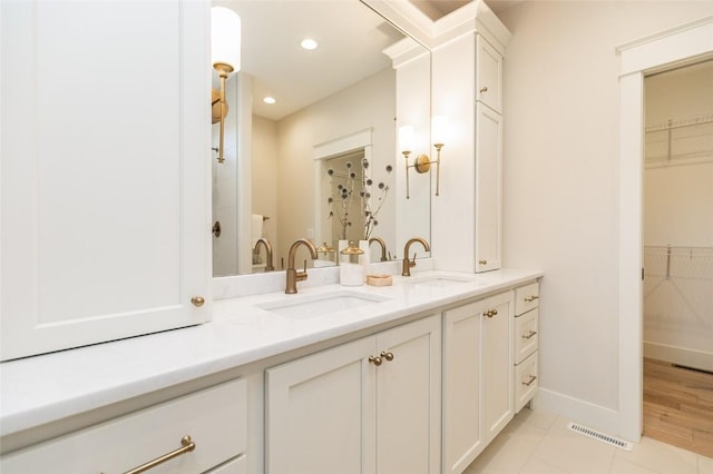 full bathroom featuring a sink, visible vents, a spacious closet, and double vanity