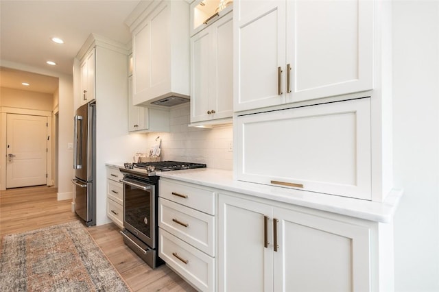 kitchen with backsplash, light wood-style floors, appliances with stainless steel finishes, white cabinets, and custom exhaust hood