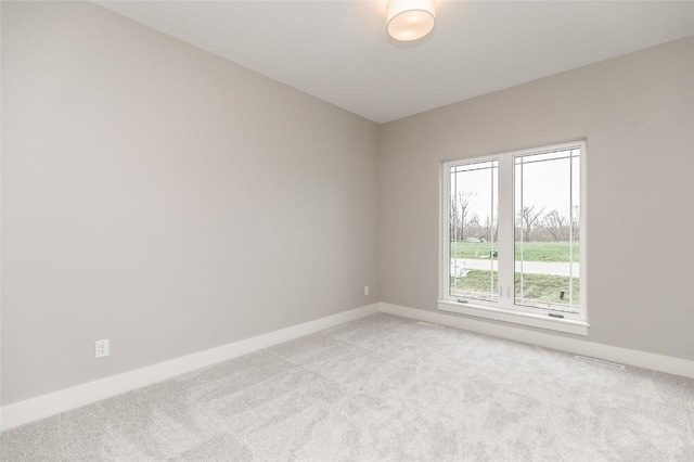 empty room featuring light carpet and baseboards