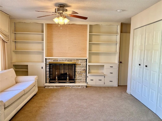 unfurnished living room featuring built in features, carpet, a ceiling fan, a fireplace, and a textured ceiling