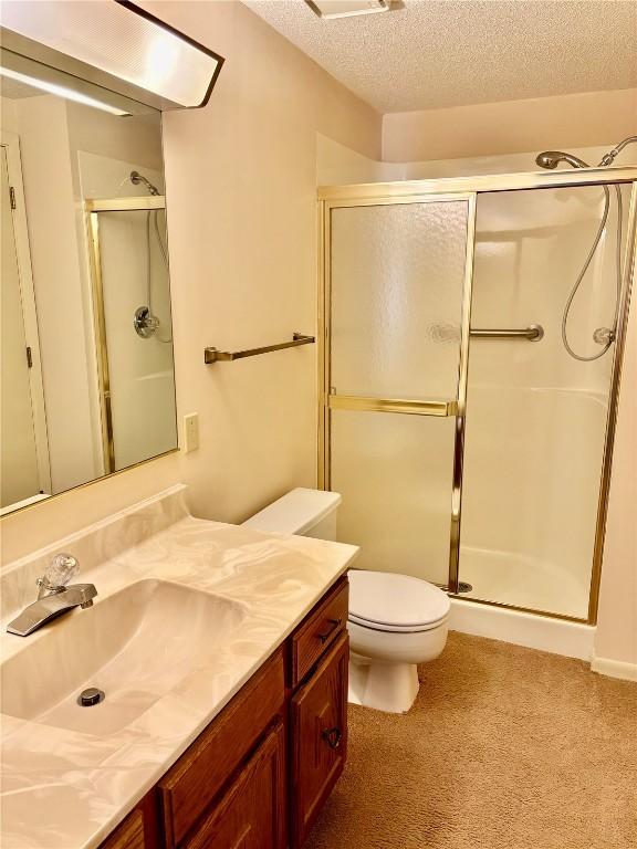 bathroom with a shower stall, a textured ceiling, vanity, and toilet