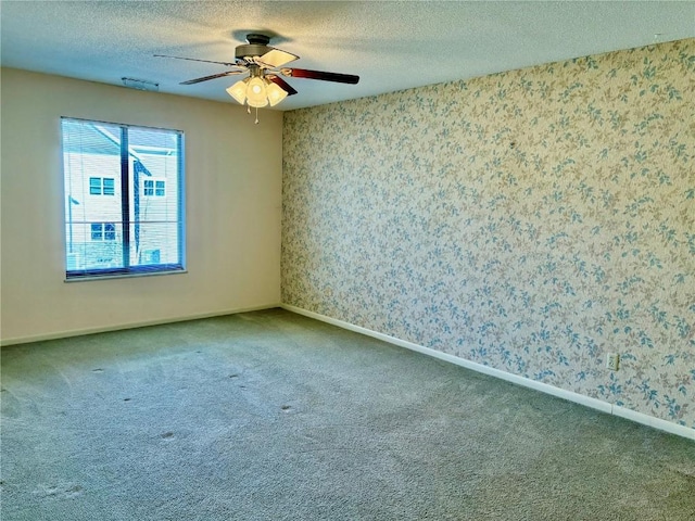 carpeted empty room featuring a textured ceiling, ceiling fan, and wallpapered walls