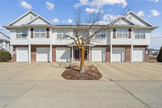 view of front of home featuring brick siding, an attached garage, and concrete driveway