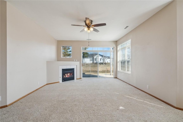 unfurnished living room with a ceiling fan, visible vents, baseboards, carpet floors, and a tiled fireplace