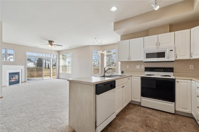 kitchen featuring a sink, open floor plan, white appliances, a peninsula, and white cabinets