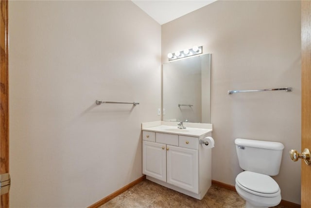 bathroom featuring toilet, vanity, and baseboards