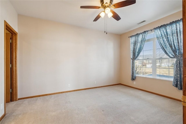 spare room with baseboards, light colored carpet, visible vents, and ceiling fan