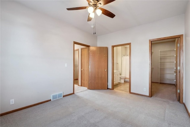 unfurnished bedroom featuring a spacious closet, visible vents, baseboards, light carpet, and ensuite bath