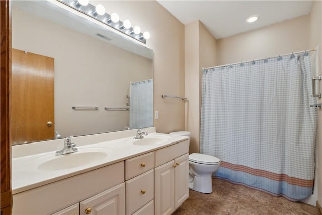 bathroom featuring double vanity, visible vents, toilet, and a sink