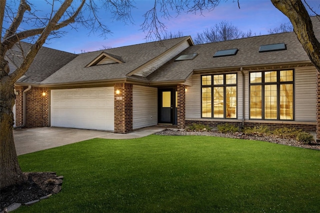 view of front of home with driveway, roof with shingles, a front yard, a garage, and brick siding