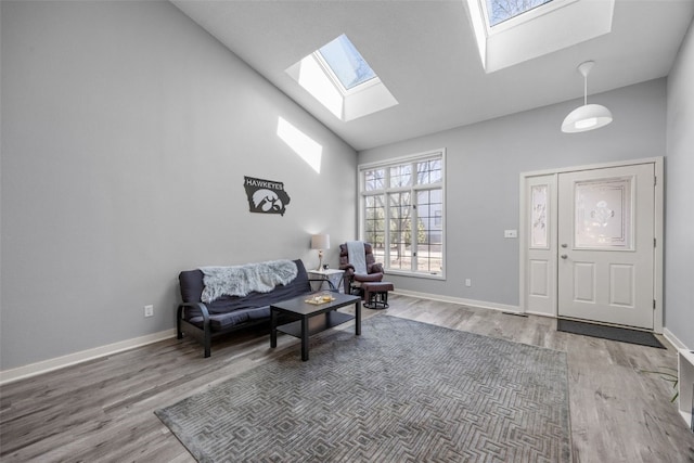 sitting room featuring baseboards, wood finished floors, high vaulted ceiling, and a skylight