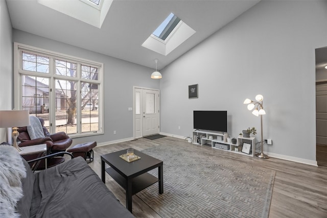 living area featuring high vaulted ceiling, a skylight, baseboards, and wood finished floors