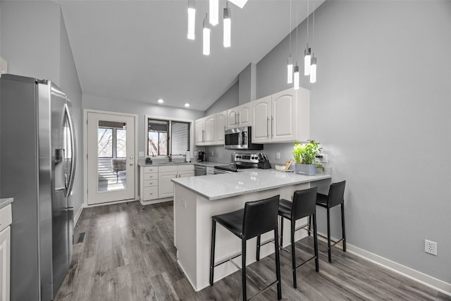 kitchen with white cabinetry, a peninsula, dark wood-style floors, and stainless steel appliances