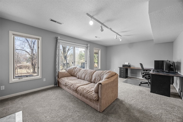 home office featuring visible vents, baseboards, carpet floors, rail lighting, and a textured ceiling