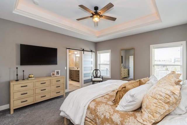 bedroom featuring a tray ceiling, carpet floors, baseboards, and a barn door