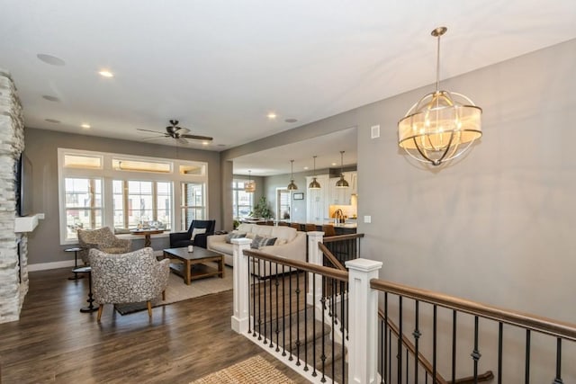 living room featuring recessed lighting, ceiling fan with notable chandelier, baseboards, and dark wood-style flooring