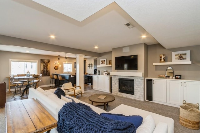 living room featuring visible vents, baseboards, decorative columns, a fireplace, and recessed lighting