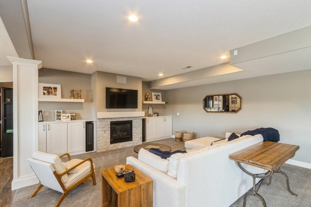 carpeted living room with recessed lighting, baseboards, a fireplace, and a sink