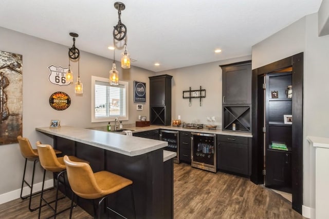 kitchen featuring beverage cooler, a peninsula, and dark wood-type flooring