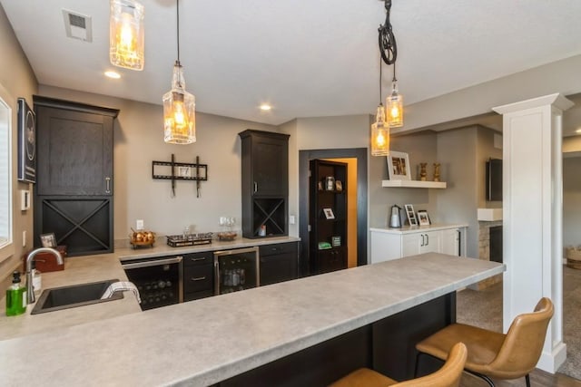 kitchen featuring light countertops, wine cooler, visible vents, and a sink