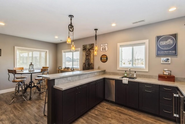 kitchen with visible vents, light countertops, a peninsula, dark wood-style floors, and a sink