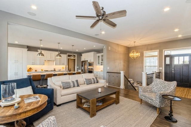 living area with recessed lighting, light wood-style floors, and ceiling fan with notable chandelier