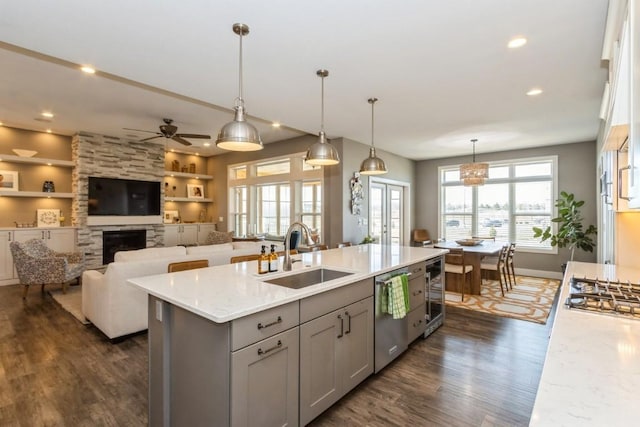 kitchen with dark wood-type flooring, gray cabinetry, a sink, light stone counters, and appliances with stainless steel finishes