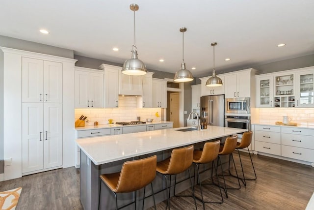 kitchen featuring dark wood-style floors, white cabinetry, stainless steel appliances, and an island with sink