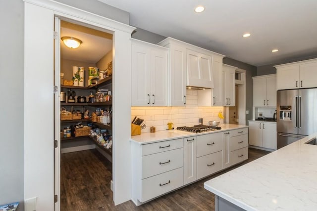 kitchen with recessed lighting, dark wood-type flooring, white cabinets, appliances with stainless steel finishes, and tasteful backsplash