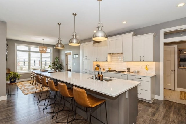 kitchen with dark wood finished floors, tasteful backsplash, stainless steel gas cooktop, and a sink