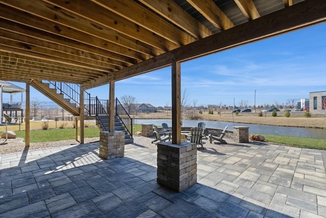 view of patio featuring stairway, a water view, and an outdoor fire pit