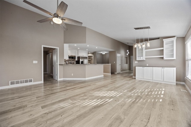 unfurnished living room featuring baseboards, visible vents, lofted ceiling, light wood-style flooring, and ceiling fan