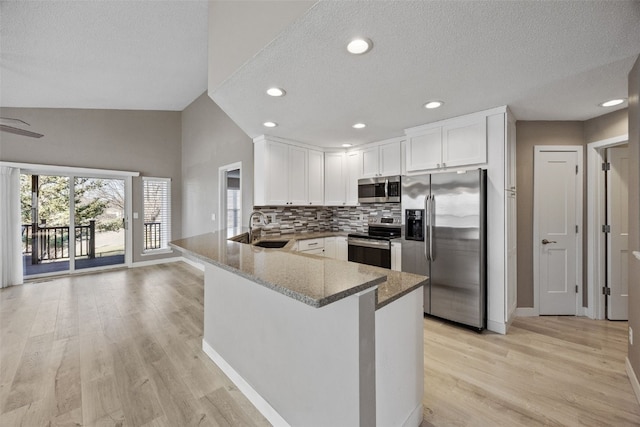 kitchen with light wood-style flooring, a sink, stainless steel appliances, white cabinets, and stone counters