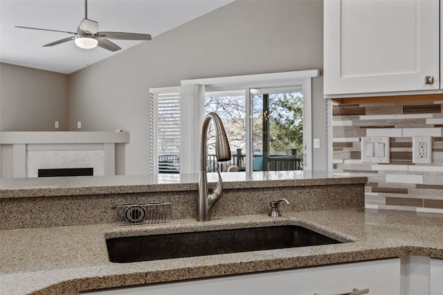 kitchen with vaulted ceiling, light stone countertops, and a sink