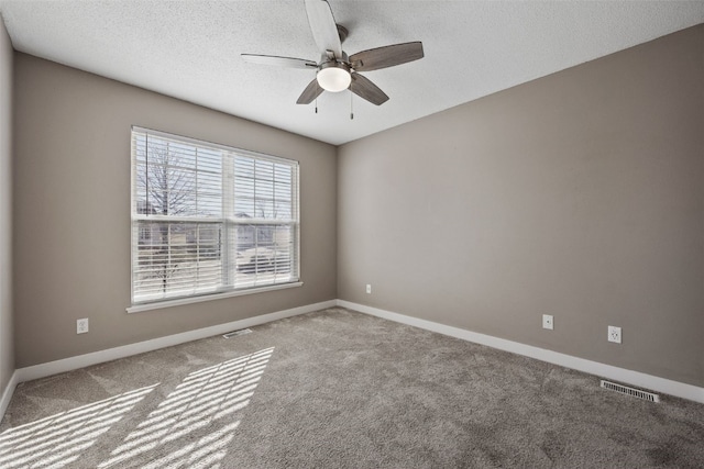 spare room with carpet, baseboards, visible vents, ceiling fan, and a textured ceiling