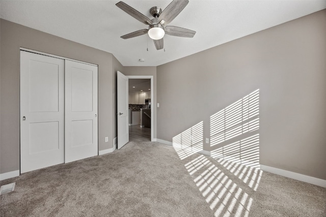 unfurnished bedroom with a closet, carpet floors, baseboards, and ceiling fan